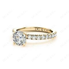 Round cut claw set diamond ring with pave set side stone in 18K Yellow