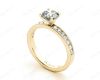 Round Cut Four Claw Set Diamond Ring with Channel Set Side Stones Down The Shoulders in 18k Yellow Gold